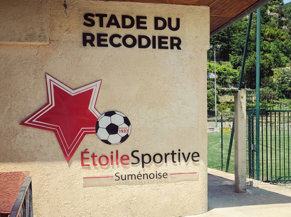 Enseigne commerciale blanche en relief avec lettres tridimensionnelles "shop" suspendue à une potence métallique noire sur façade urbaine